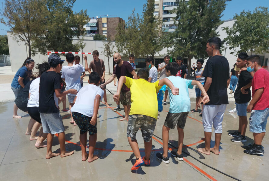 joves realitzant una activitat d'aigua en un pati d'escola